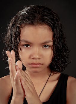 Close-up portrait of a young girl with wet hair, showing a determined expression against a dark background.