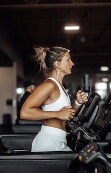 Athletic woman focused on her workout running on a gym treadmill, emphasizing fitness and health.