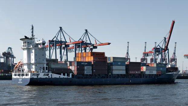 A container ship in Hamburg port with cranes loading cargo for global trade.