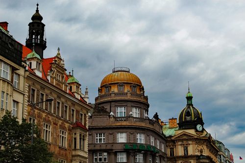 Dramatic view of historical buildings under a cloudy Prague sky in the city center.