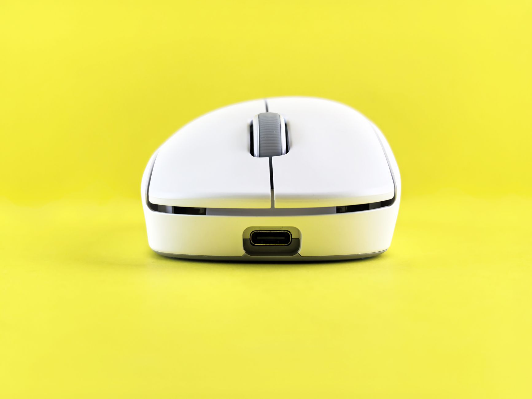 Close-up of a sleek white wireless mouse against a vibrant yellow backdrop for modern tech themes.