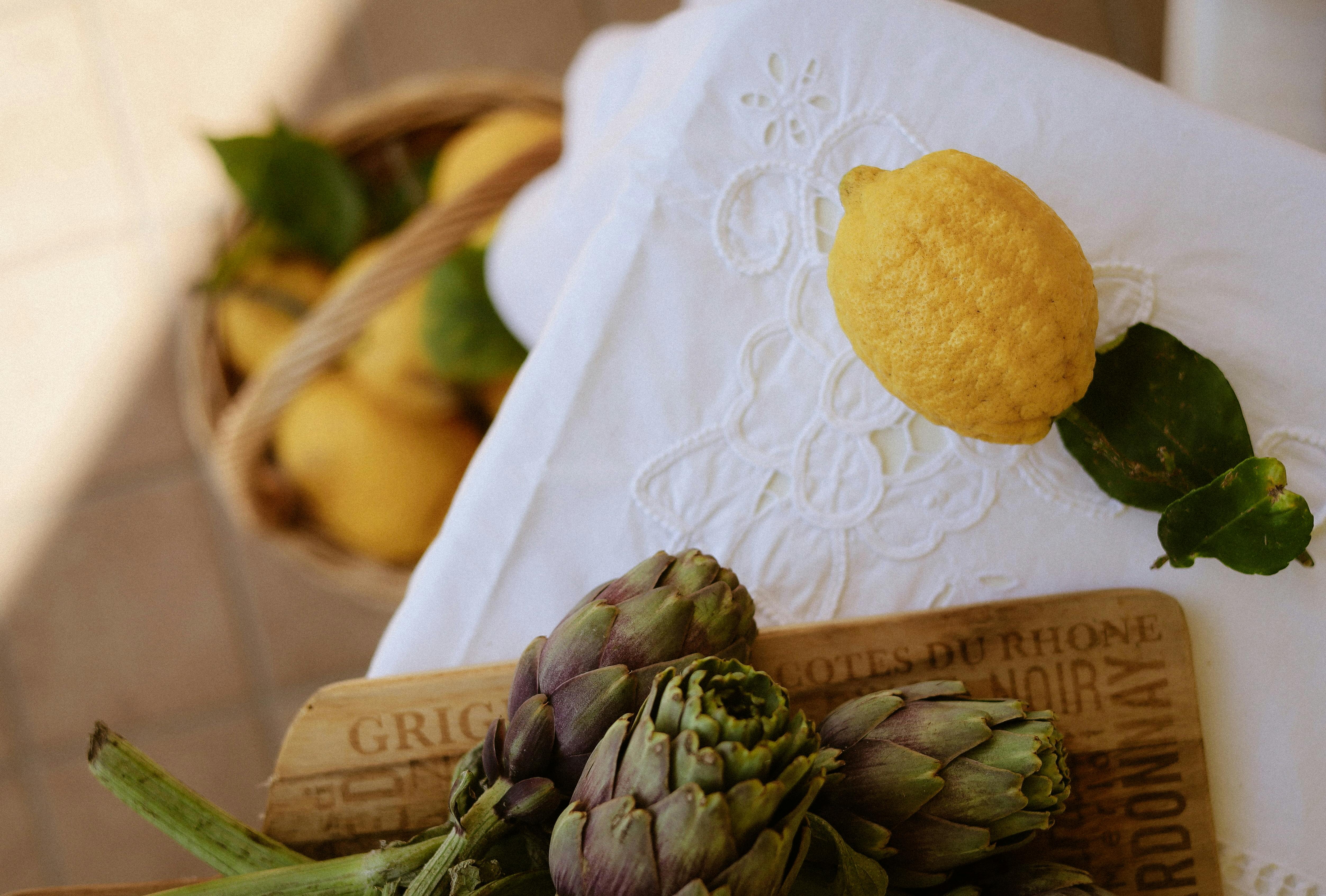 Lemons and artichokes on rustic table setting, perfect for a culinary theme.