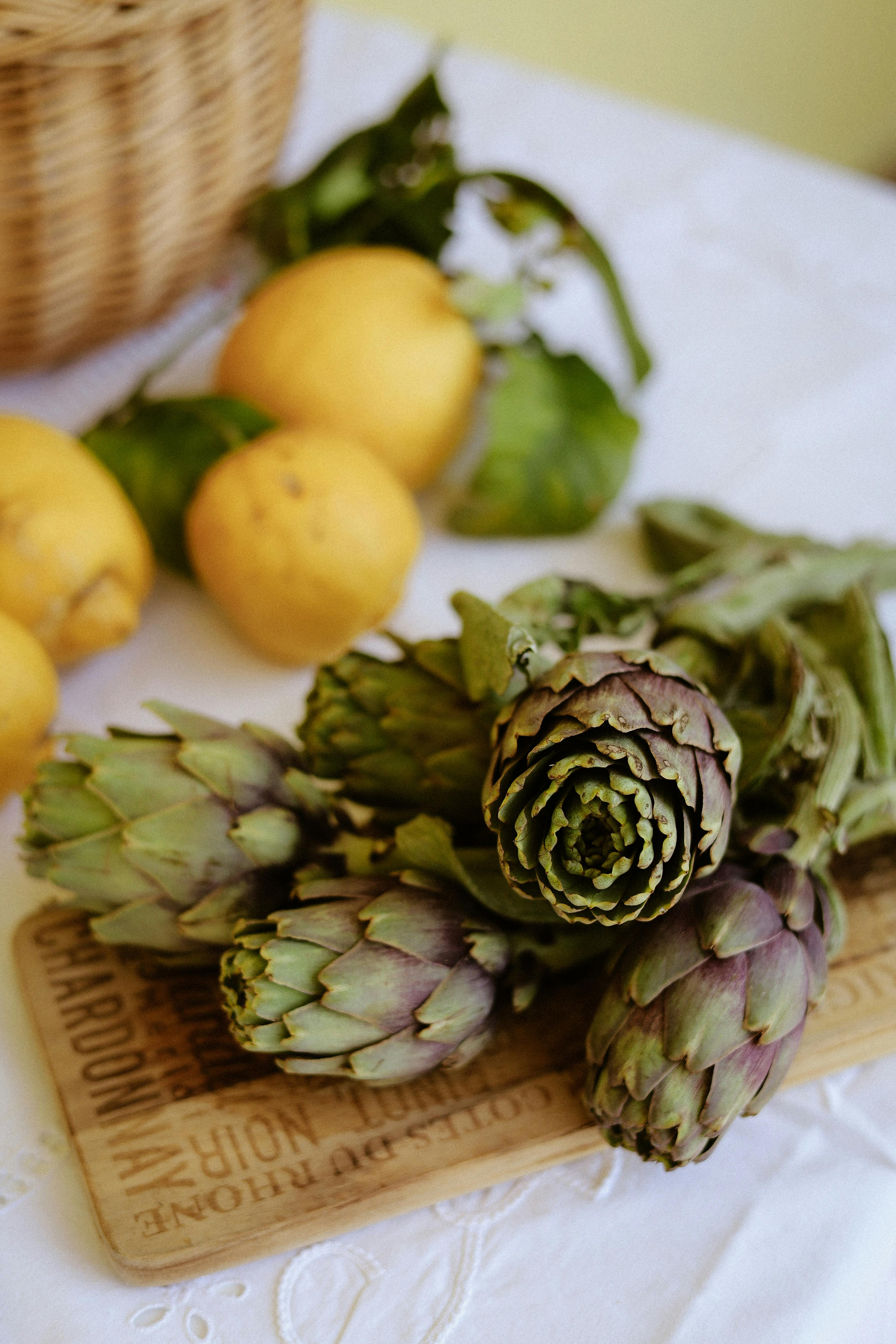 A vibrant display of fresh artichokes and lemons on a rustic table evokes a Mediterranean feel.