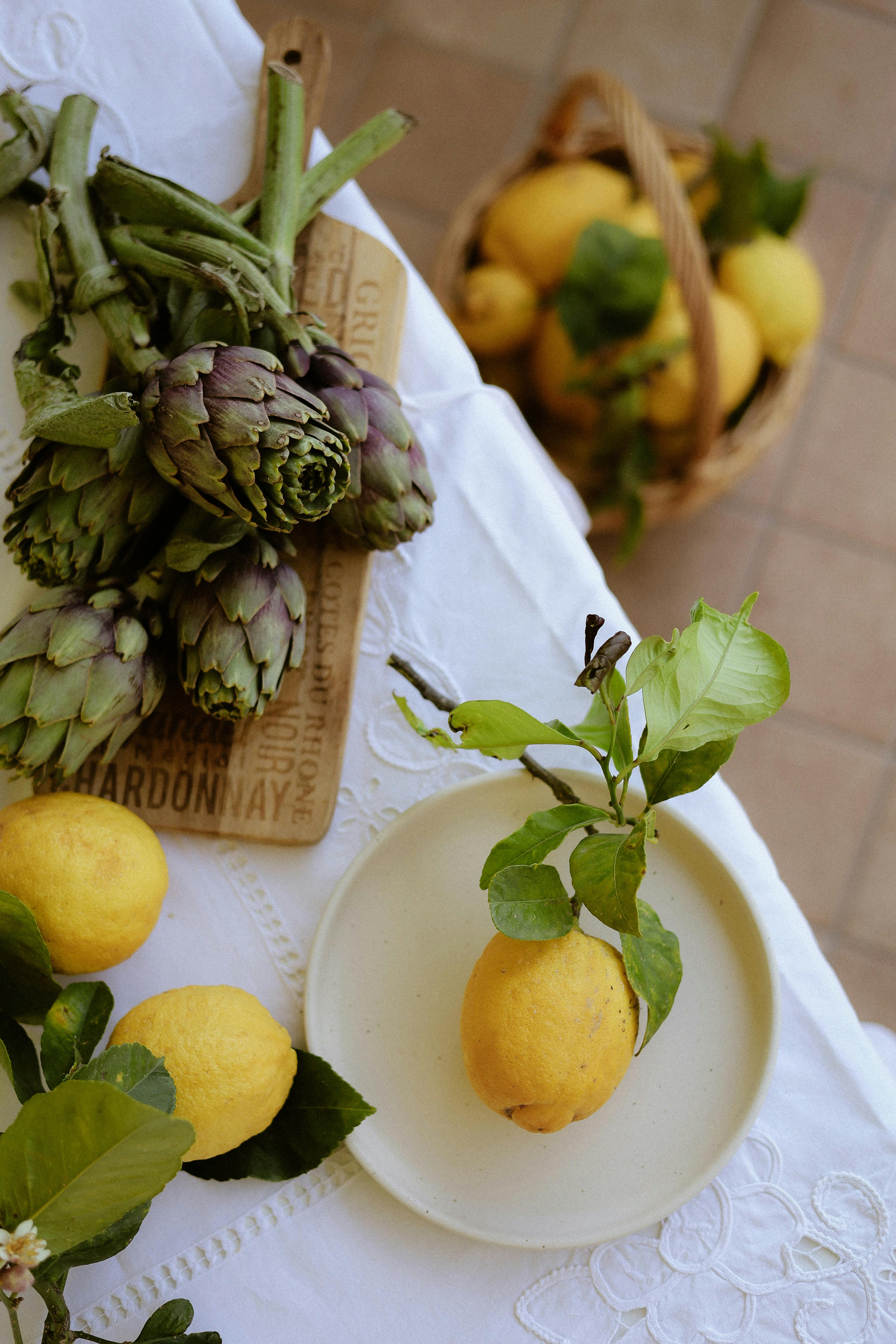 Artfully arranged lemons and artichokes on a rustic table setting.