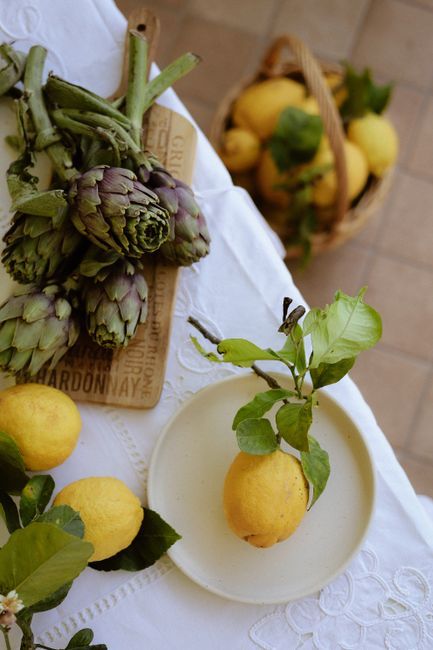 Artfully arranged lemons and artichokes on a rustic table setting.