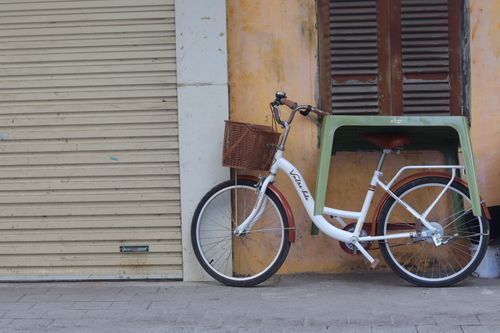 Free White bicycle with basket against a weathered wall in Hanoi, Vietnam creates a vintage urban scene. Stock Photo