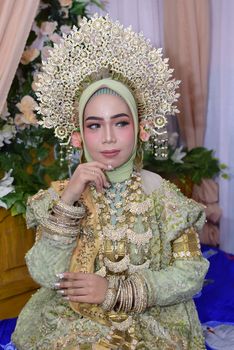 A stunning Bugis bride adorned in traditional attire and ornate jewelry during a cultural wedding ceremony. - Fotografer Sidoarjo
