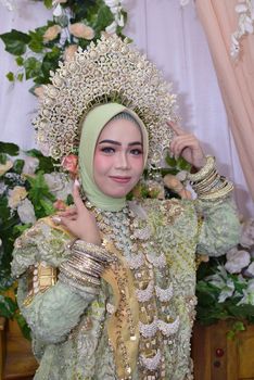 A Bugis bride in ornate green attire and headdress, showcasing cultural beauty. - Fotografer Sidoarjo
