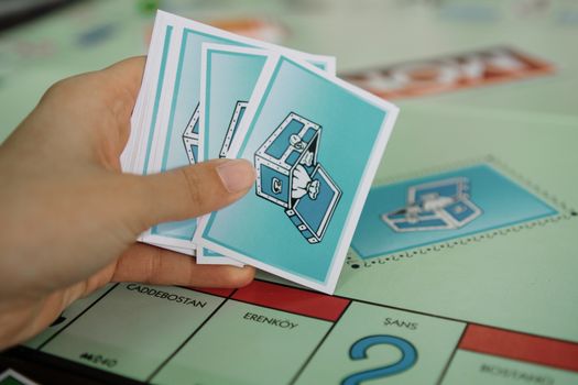 Close-up of a hand holding chance cards over a Monopoly board with property spaces visible.