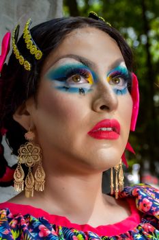 Close-up portrait of a drag queen in colorful makeup and traditional costume outdoors.