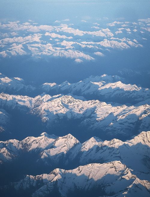 Free Breathtaking aerial view of the Alps with snow-covered peaks under a clear blue sky. Stock Photo