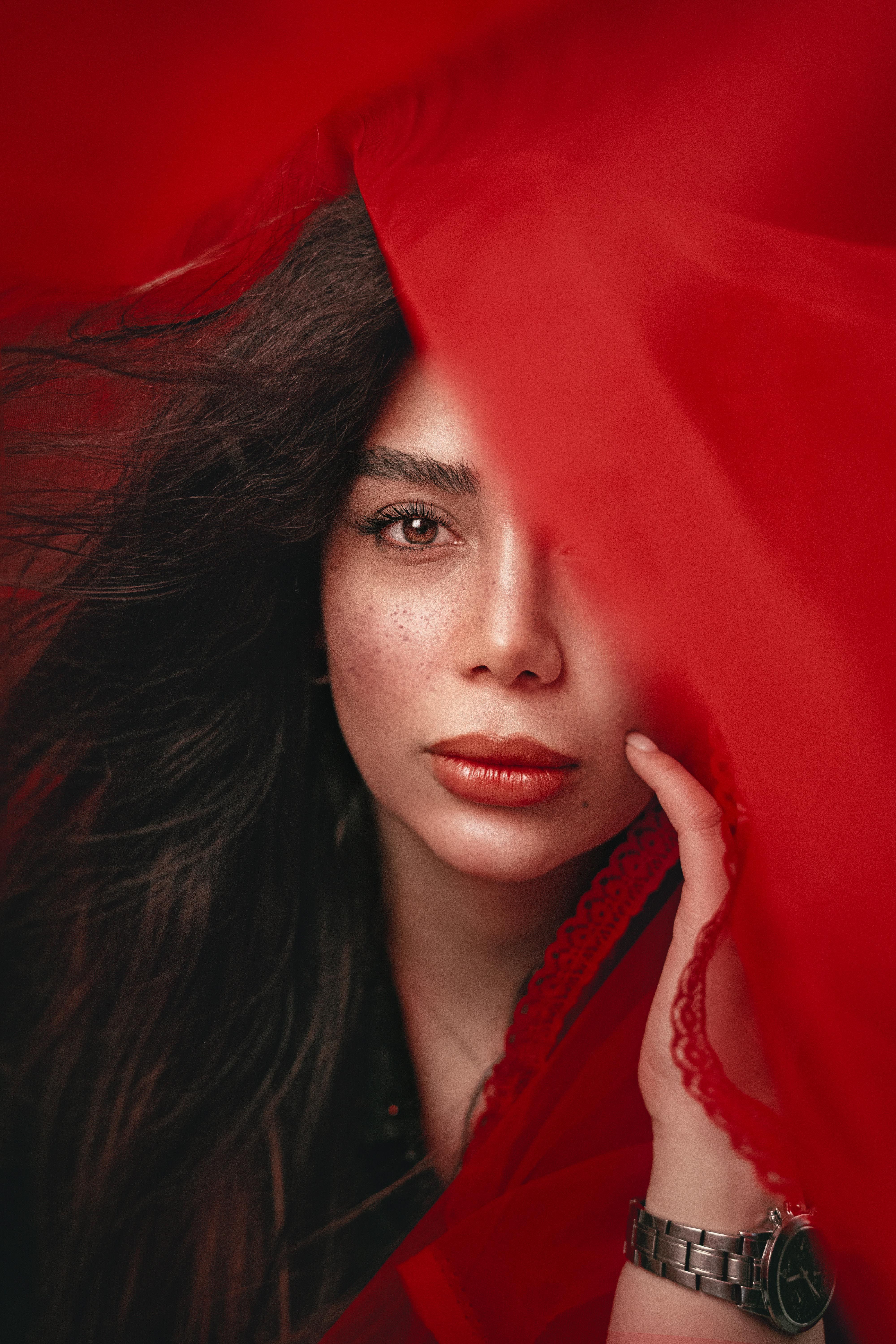 Artistic portrait of a woman partially covered with a red fabric, showcasing elegance and mystery.