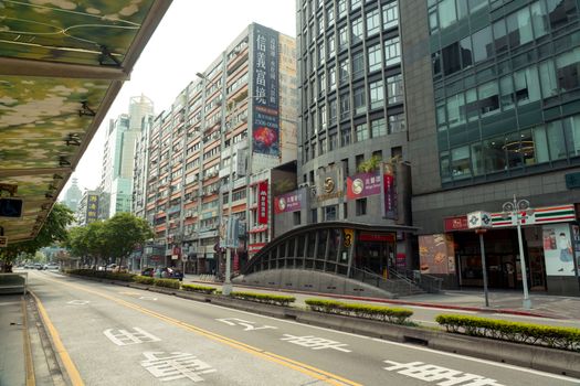 City street with modern skyscrapers, shops, and bilingual signage on a quiet day.