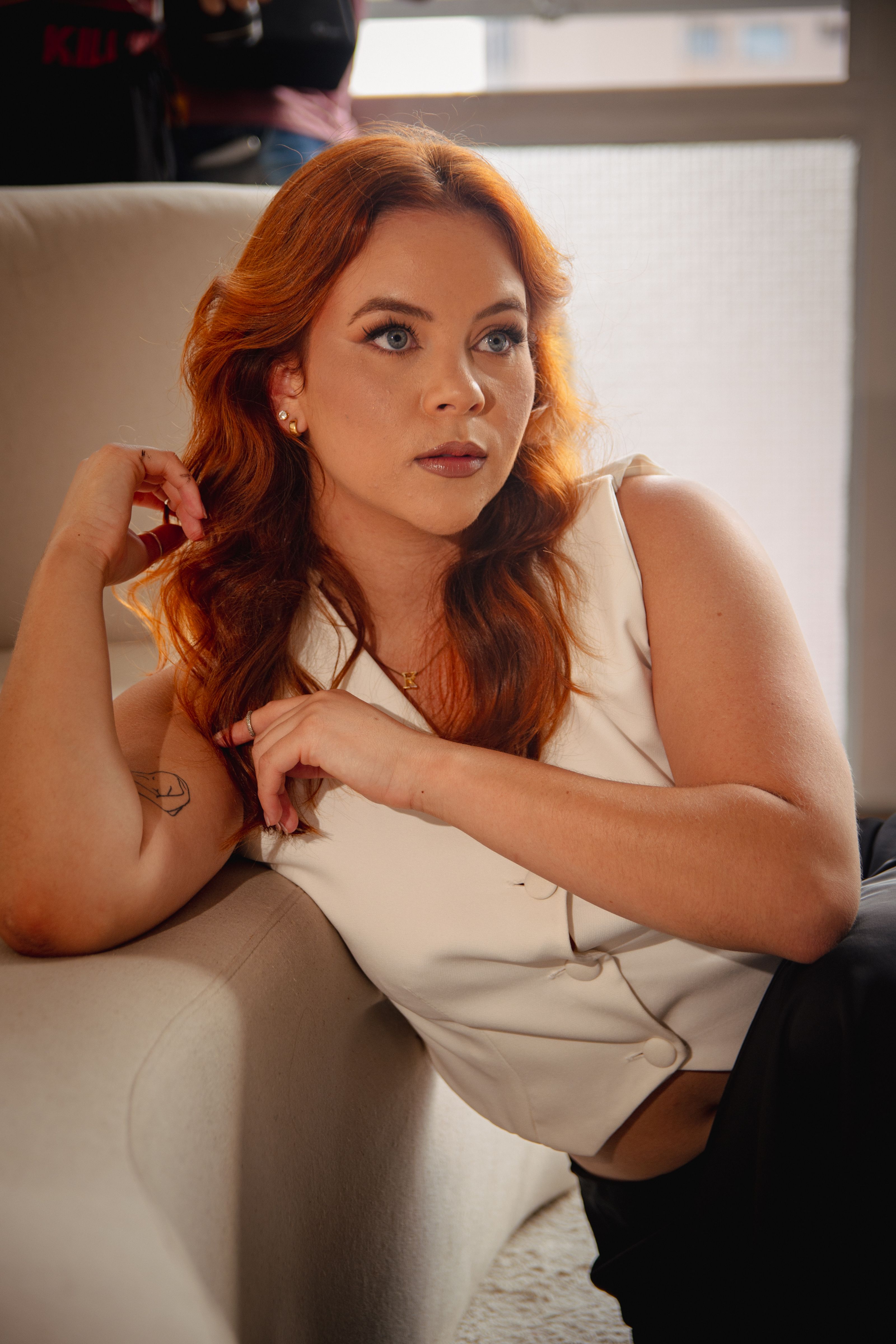 A woman with red hair relaxing on a couch, exuding a calm and introspective mood.