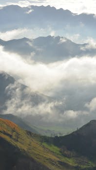 Breathtaking view of mountain ridges and clouds in the Spanish landscape, creating a serene and layered appearance.