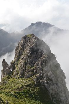 Explore the serene beauty of a rocky mountain peak enveloped in mist, capturing the tranquil essence of nature.