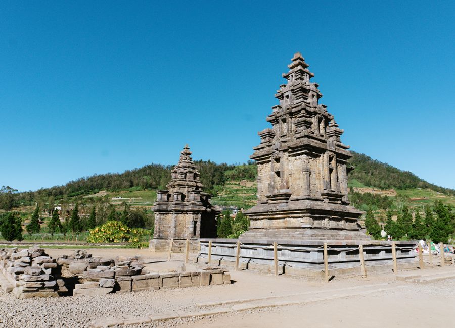 Historic Hindu temple in lush landscape under a vivid blue sky, perfect for cultural and travel themes.