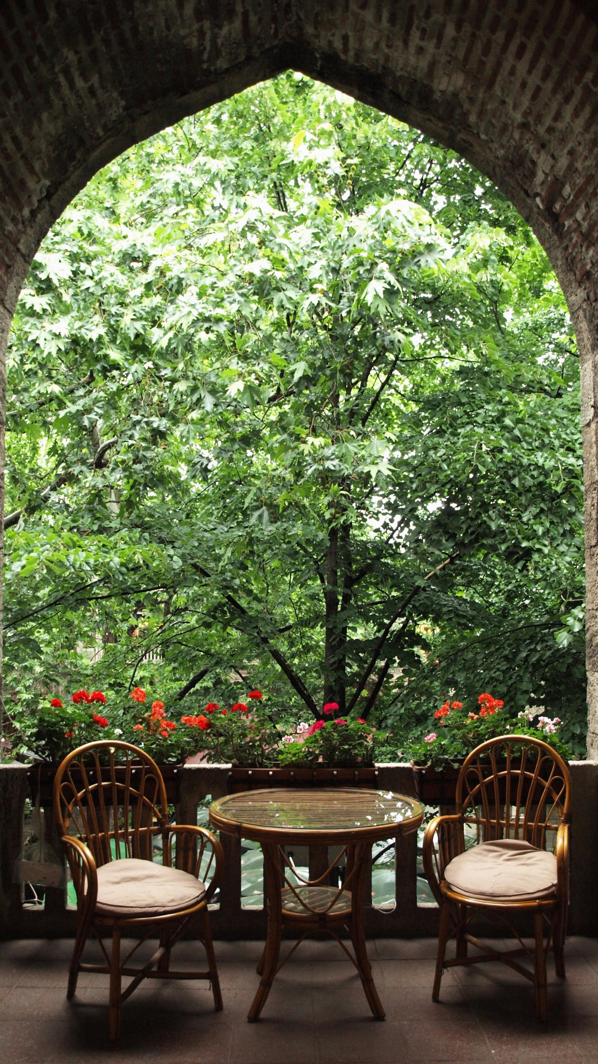 Inviting balcony with chairs and table offering a serene view of a lush green garden.