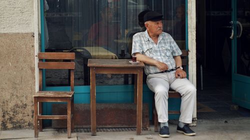 Free Senior man enjoys tea outside a cafe, evoking a sense of calm and contemplation. Stock Photo
