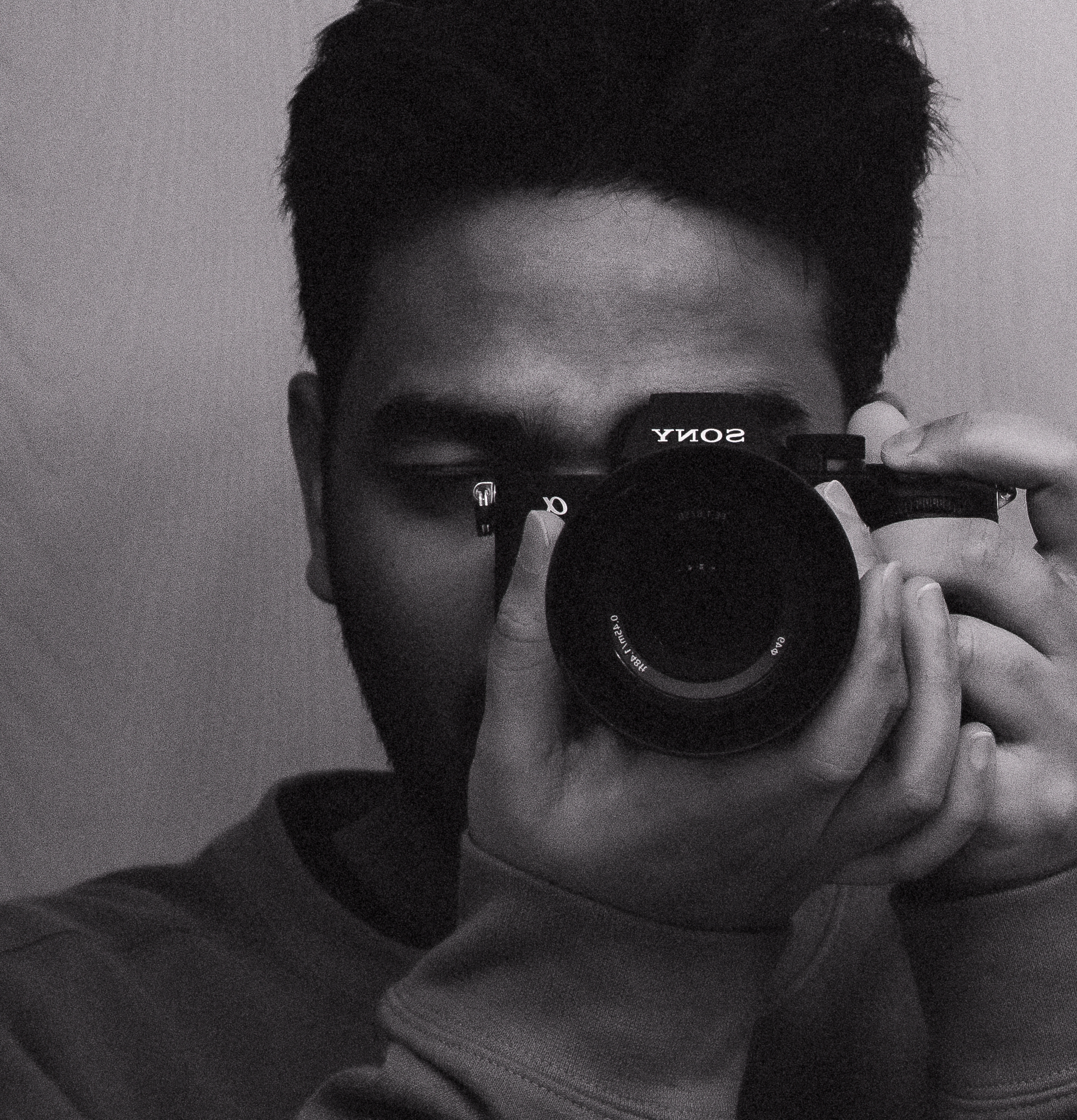 Artistic black and white photo of a young man holding a camera.