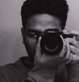 Artistic black and white photo of a young man holding a camera.