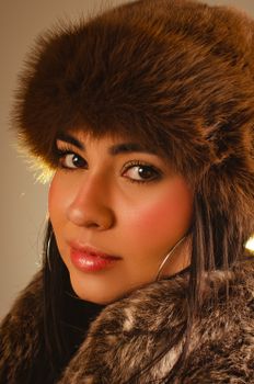 Stunning close-up portrait of a woman wearing a warm, brown fur hat and coat.