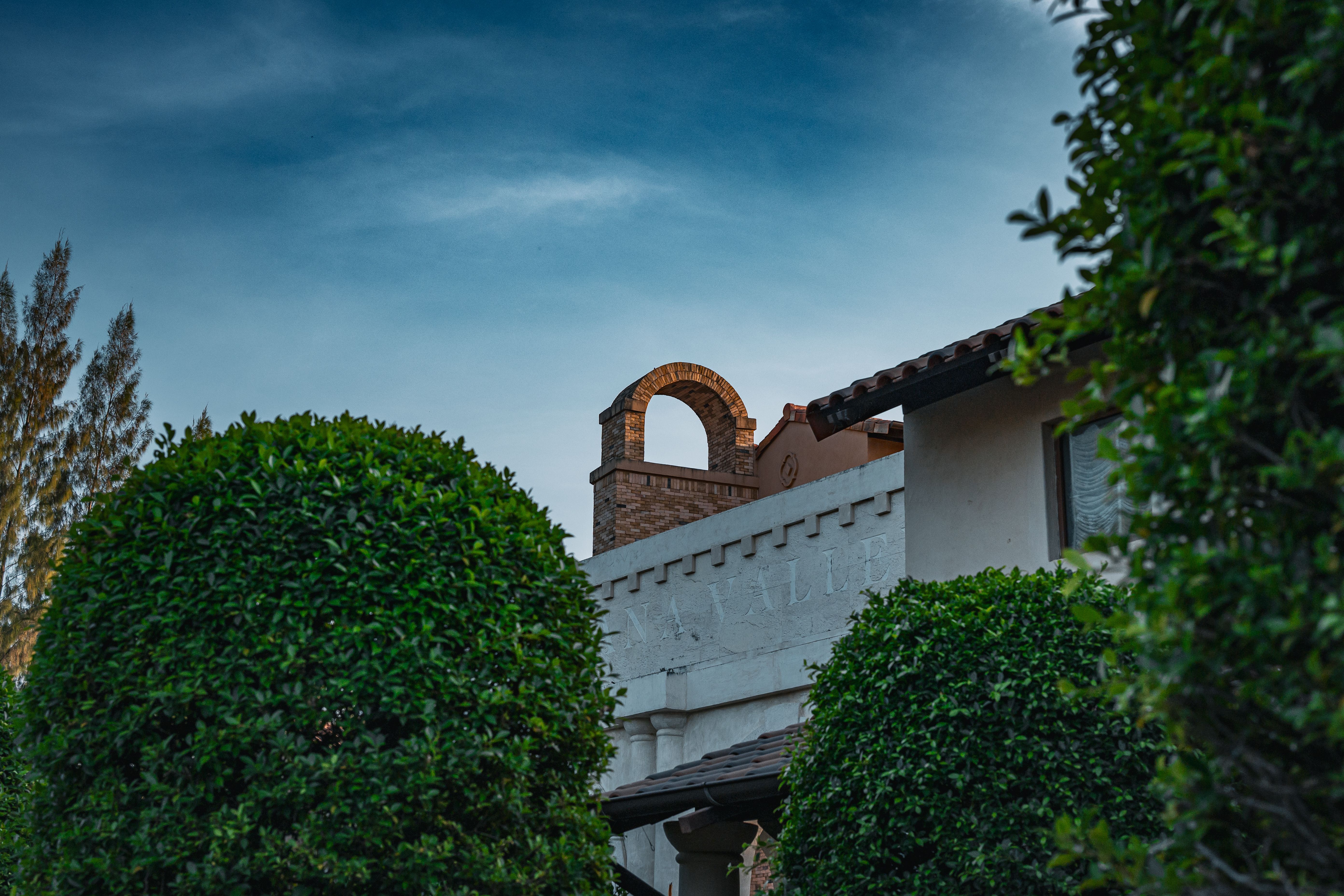 A view of traditional Thai architecture framed by lush greenery under a vibrant blue sky.