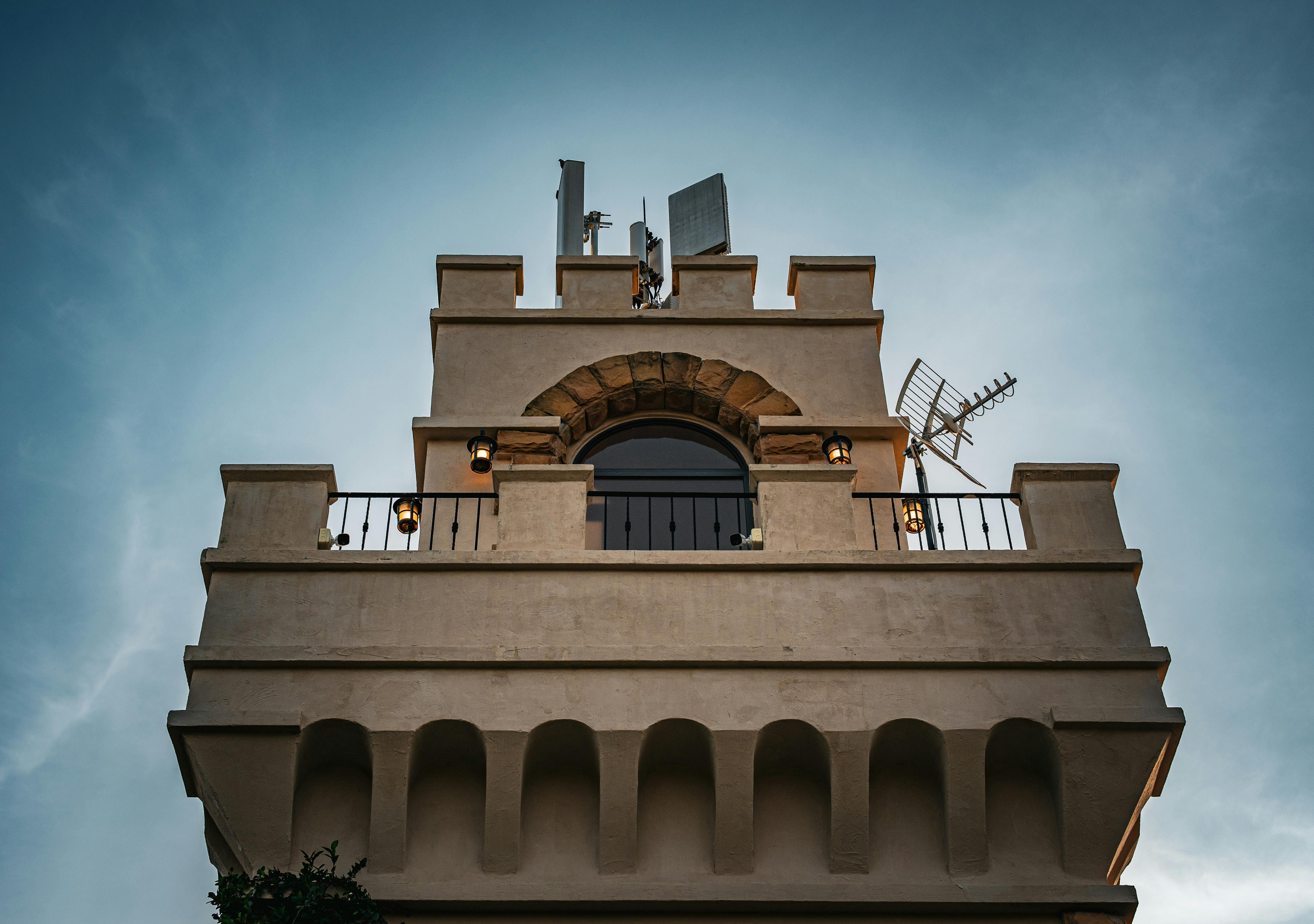 A unique Thai tower facade features modern antennas under a clear blue sky.