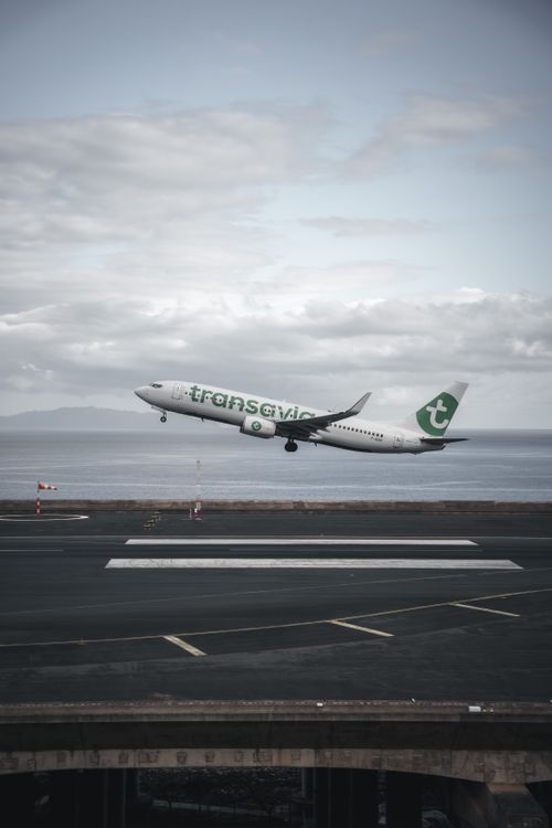 Free Transavia airplane taking off from a runway with ocean view. Stock Photo