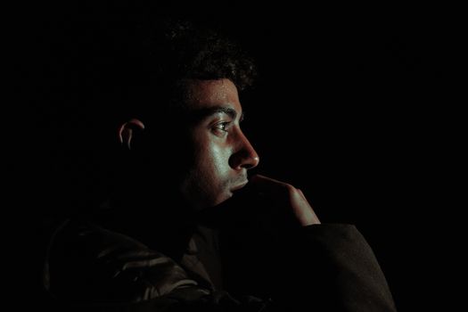 Close-up profile of a man in dramatic lighting, creating a moody atmosphere.