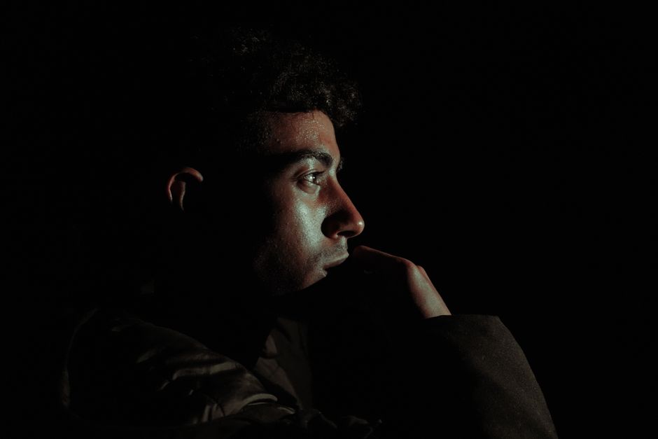 Close-up profile of a man in dramatic lighting, creating a moody atmosphere.