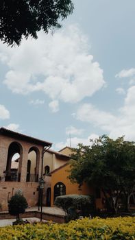 Sunny scene featuring Mediterranean architecture with lush greenery and a vibrant sky.