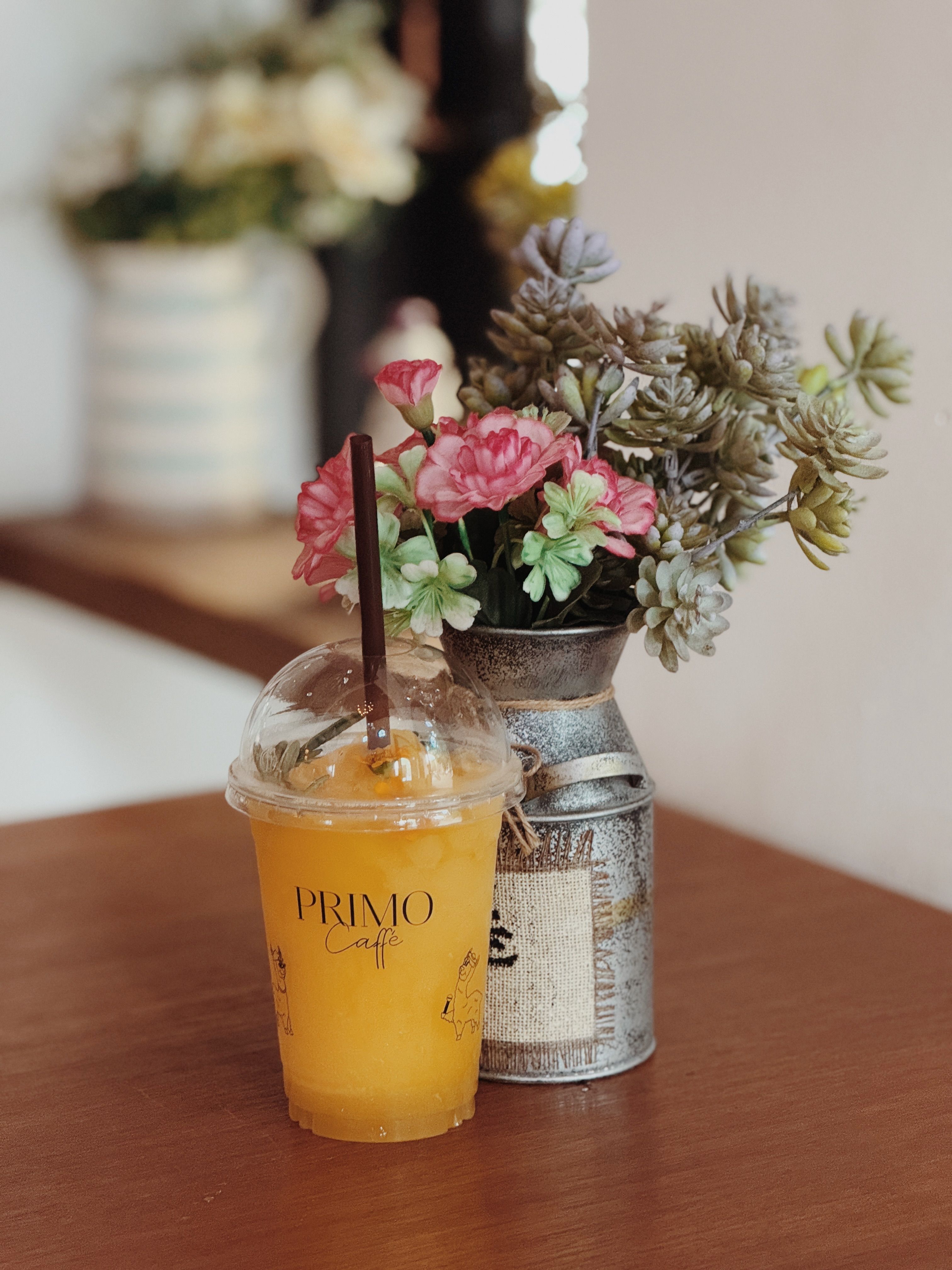 A vibrant orange juice served with a floral arrangement for a refreshing vibe.