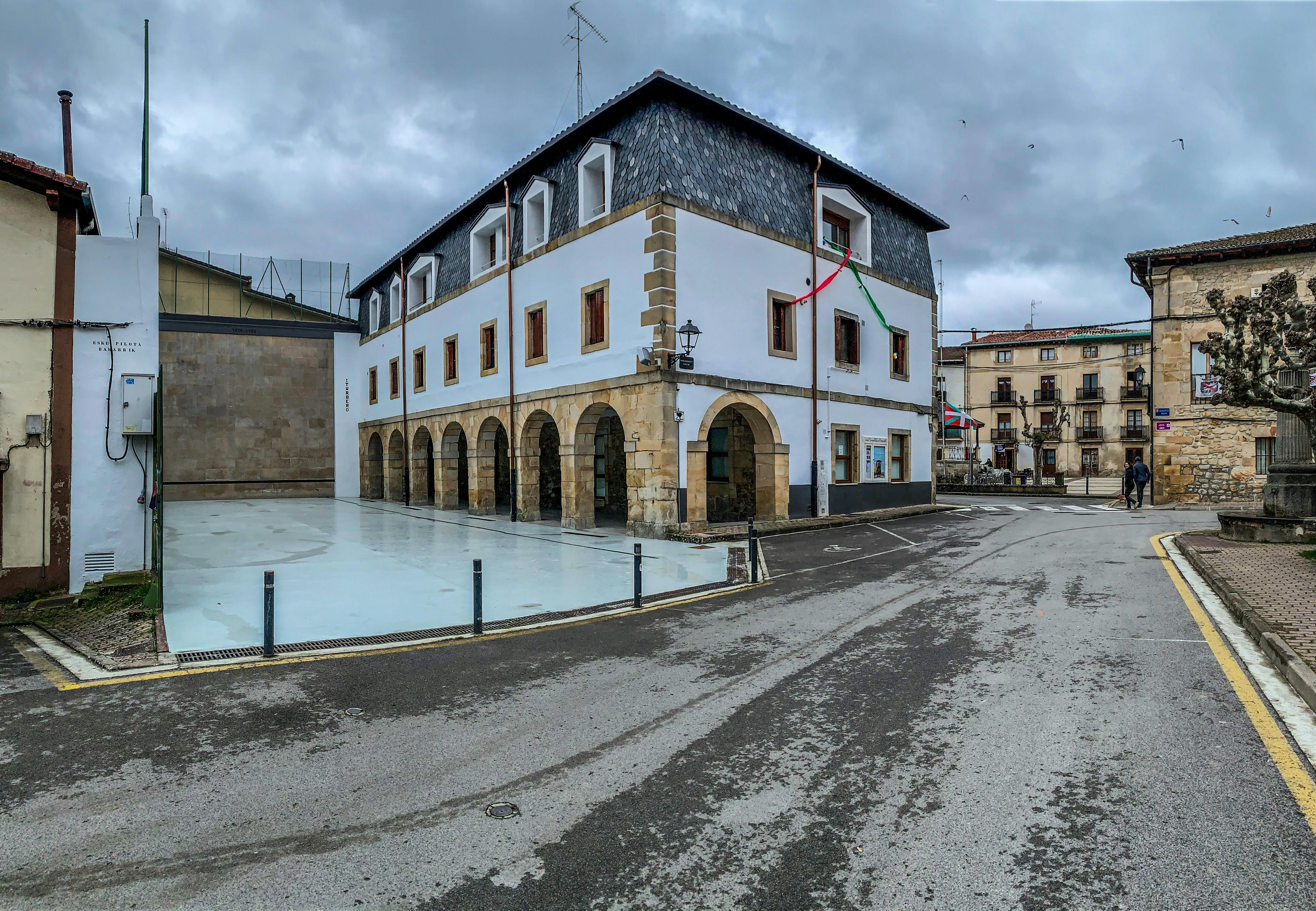 Free Charming Basque building with arches, flags in a cloudy cityscape. Stock Photo