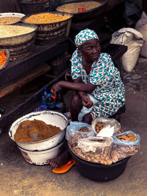 Free An elderly woman in traditional attire selling spices at a busy African market. Stock Photo