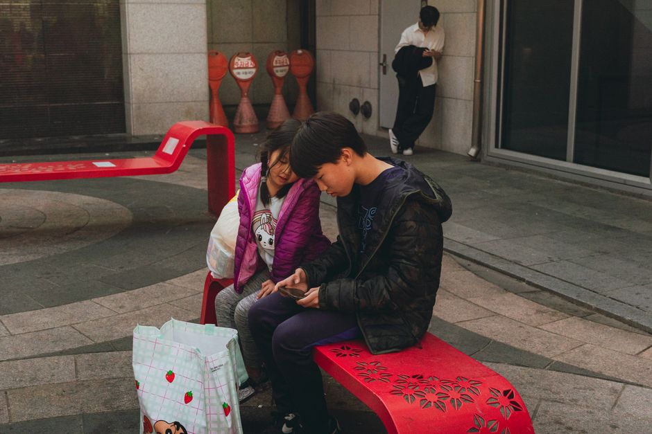 Photo by Theodore Nguyen on Pexels A candid moment of children sitting on vibrant benches in Seoul's urban environment.