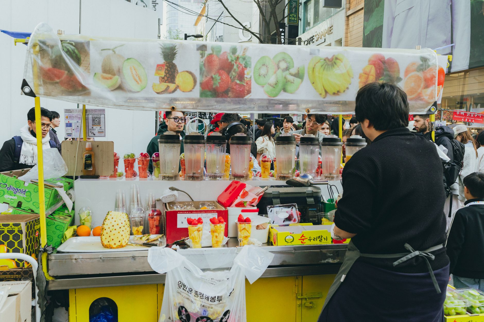 Colorful street vendor stand in Seoul, showcasing fresh fruit smoothies and vibrant city life.
