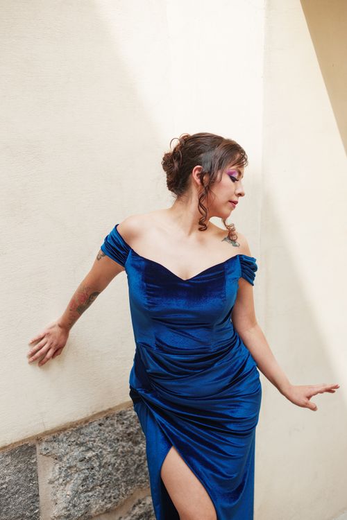 Free A woman in a stunning blue dress poses against a stone wall, exuding elegance. Stock Photo