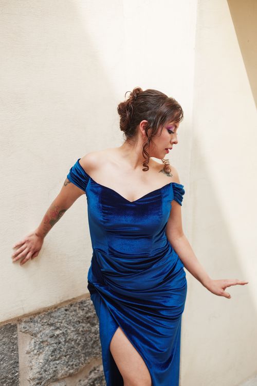 Free Elegant woman in a blue velvet dress poses stylishly against a neutral indoor backdrop, showcasing fashion and grace. Stock Photo