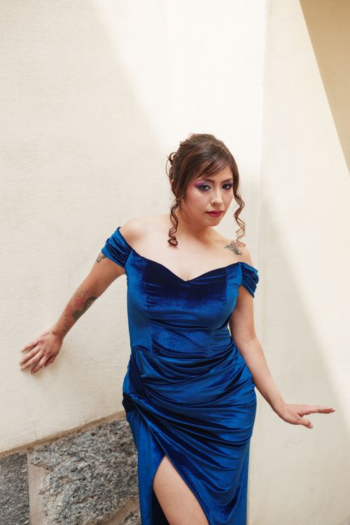Free A sophisticated woman in a striking blue velvet gown poses indoors with confidence. Stock Photo