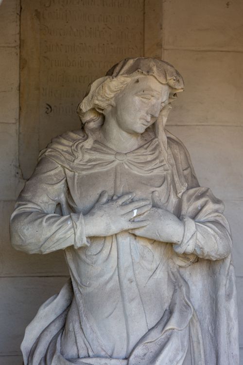 Free Detailed stone sculpture of a historical figure with a serene expression and folded hands. Stock Photo