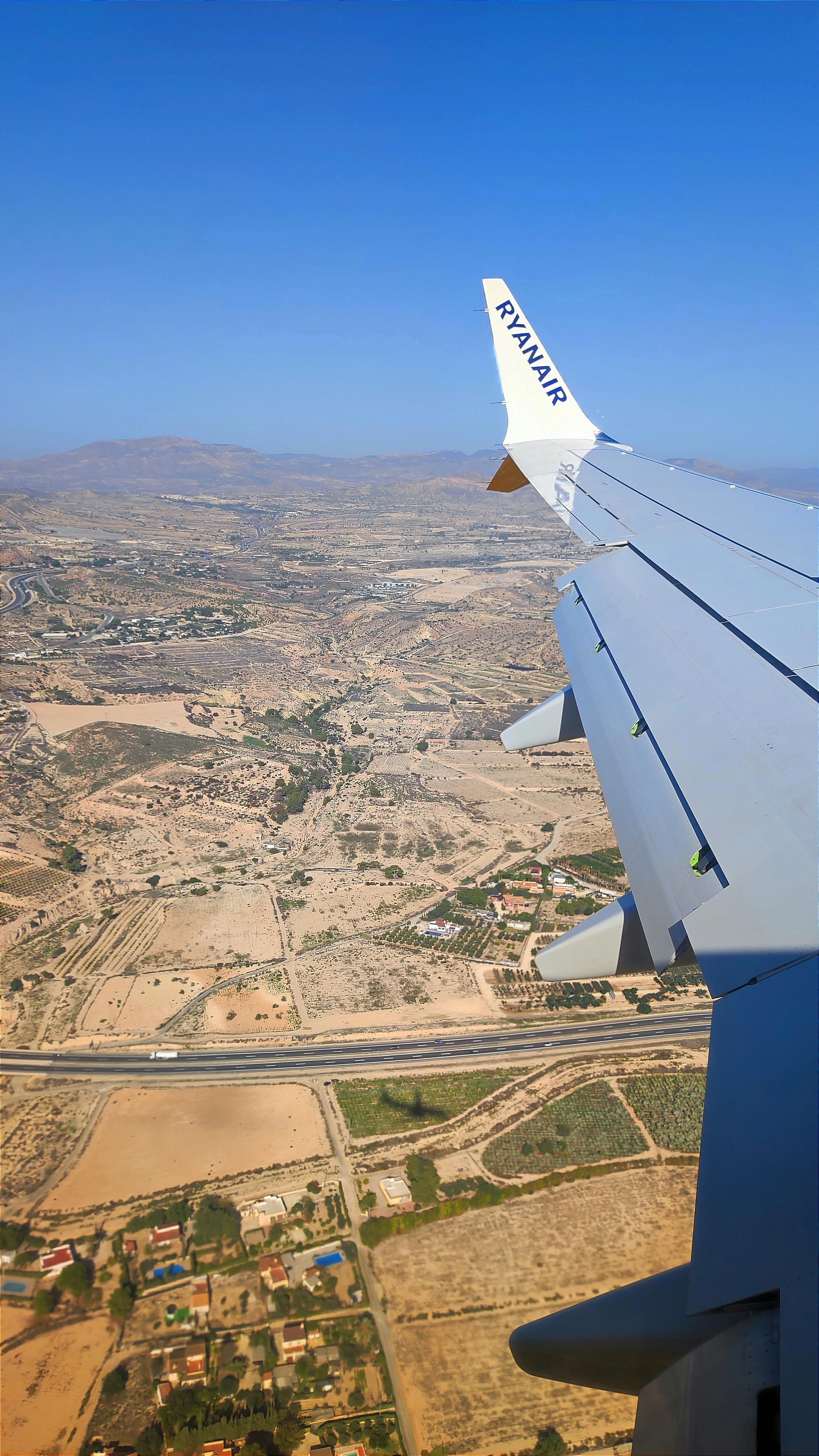 Free Scenic aerial view of Alicante, Spain from airplane wing with clear blue skies. Stock Photo