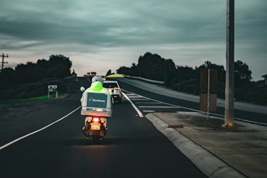 A Domino's pizza delivery scooter rides through a Melbourne street at dusk.