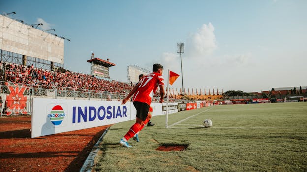 A football player takes a corner kick in a lively Indonesian stadium filled with fans.