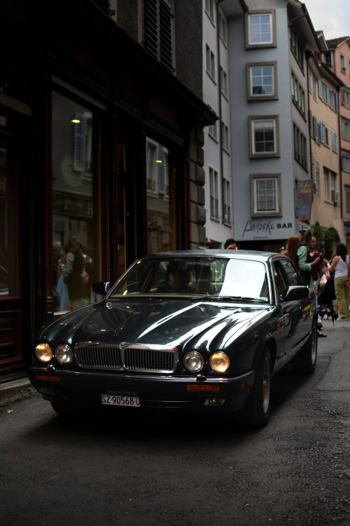 Free Classic black car parked on a narrow street in Zürich, Switzerland, with reflections on the elegant vehicle's surface. Stock Photo