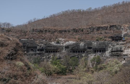 Free Ajanta Caves in Maharashtra, India carved into dry mountain landscape under clear sky. Stock Photo
