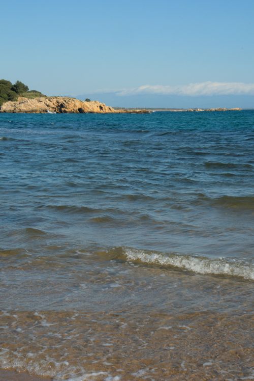 Free Tranquil sandy beach in L'Escala, Catalonia, Spain with crystal clear water and blue sky. Stock Photo