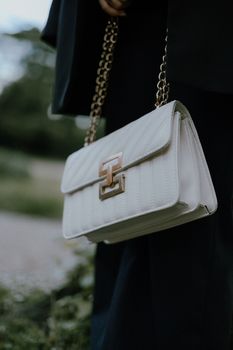 Stylish white handbag with gold chain details, perfect for any occasion.
