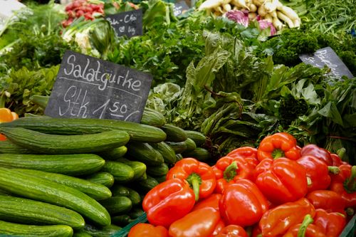 Free Vibrant fresh vegetables including cucumbers and peppers on a market stand. Stock Photo