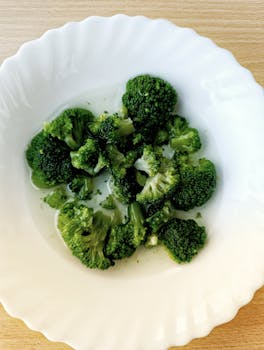 A top view of fresh steamed broccoli on a white plate, emphasizing healthy eating.